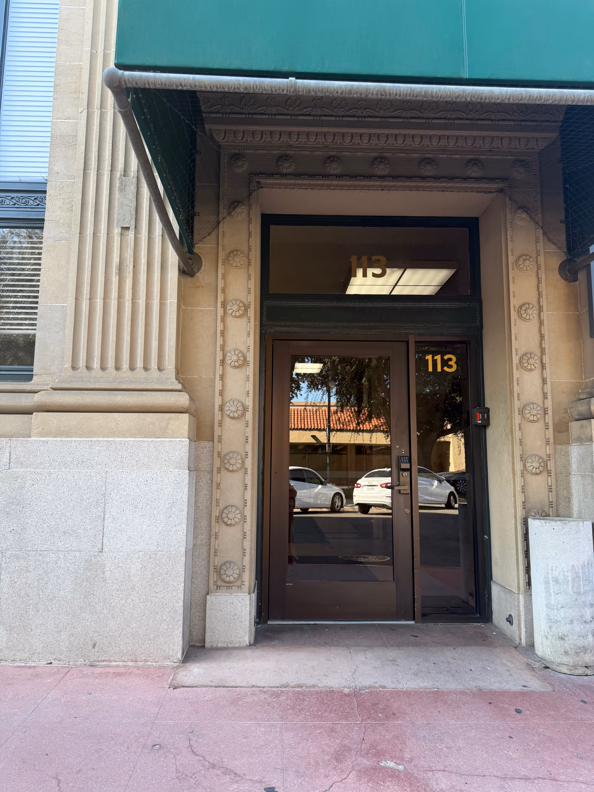 Entrance door of a stone building with decorative facade details and a green awning.