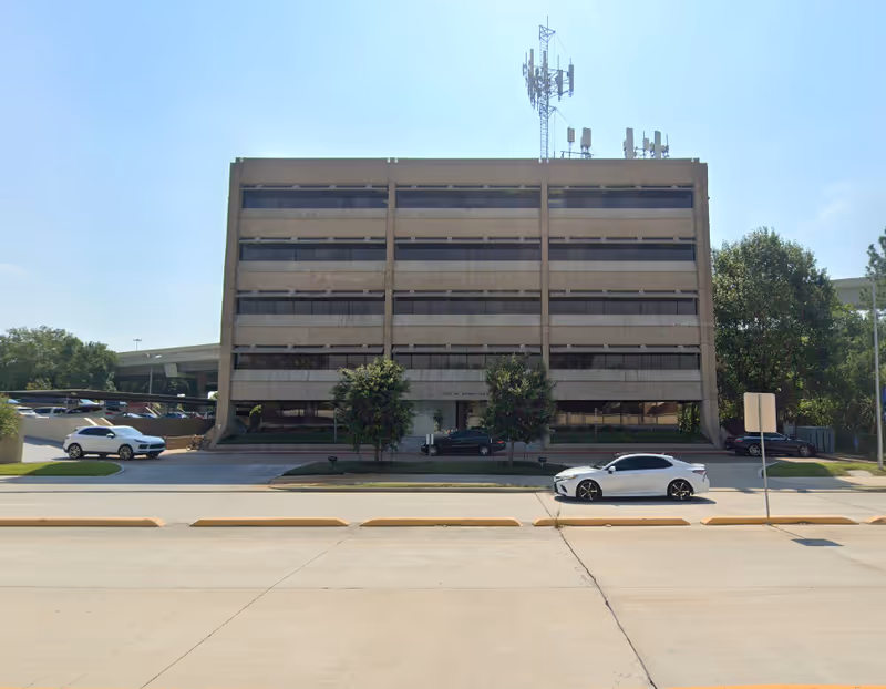 Front exterior of a multi-story building with parked cars.