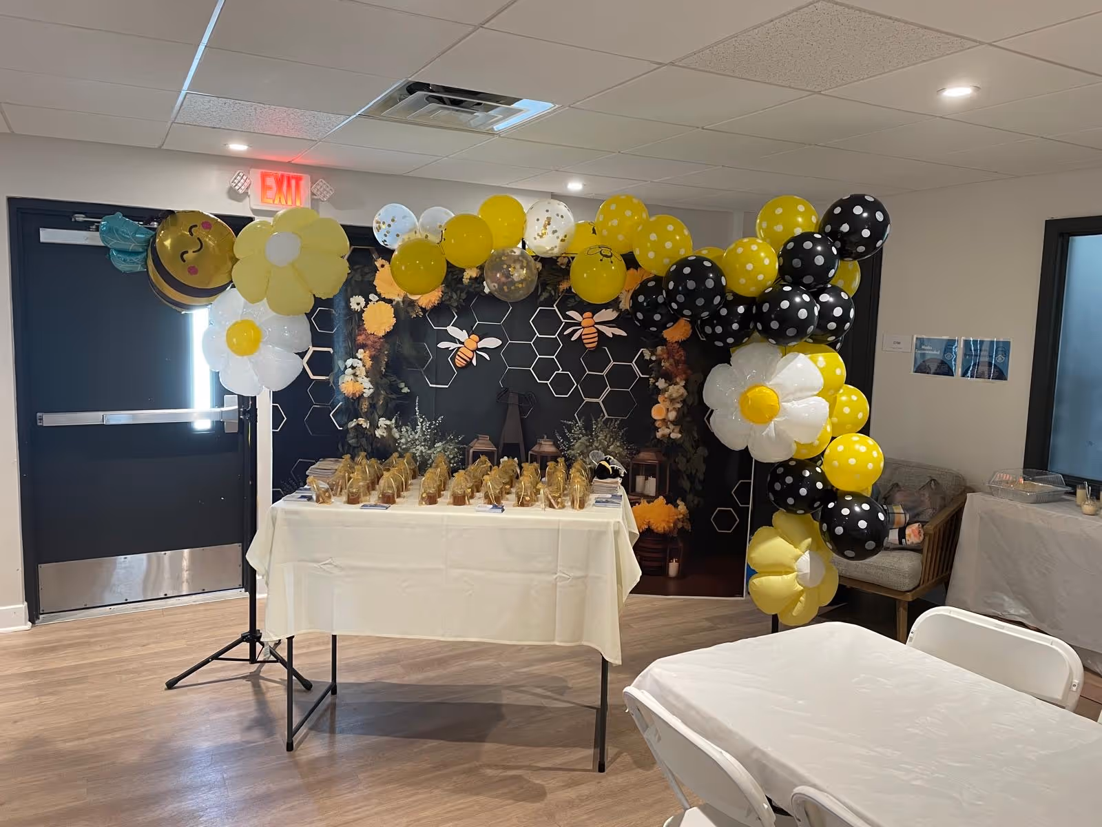 Event setup with yellow and black balloons around a table in a decorated room.