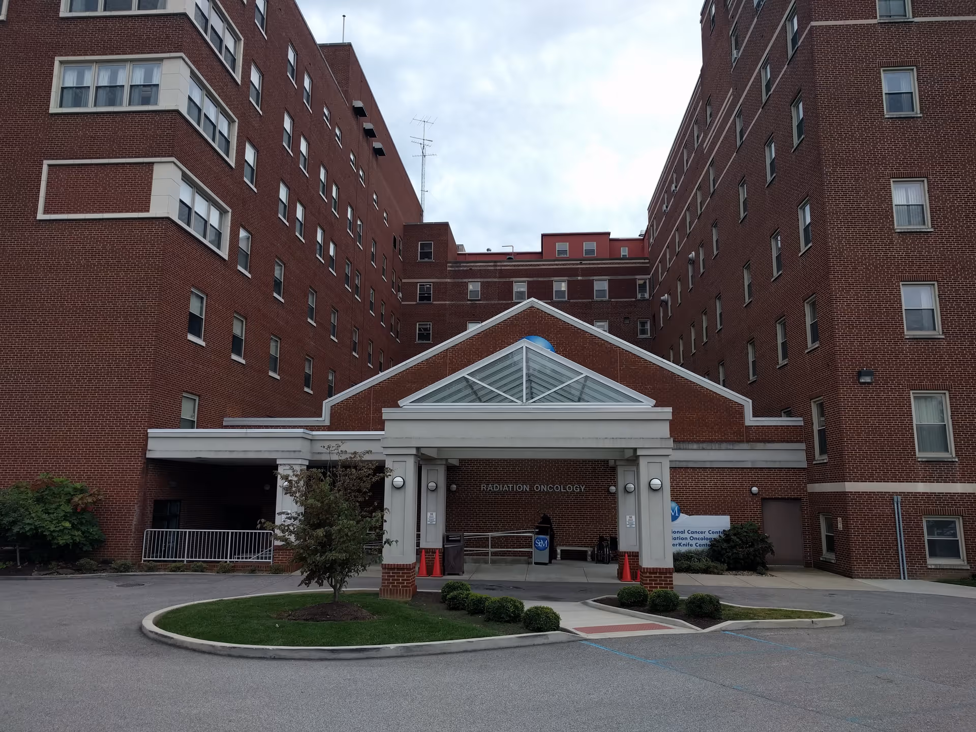 Red brick hospital exterior with a glass-paneled front entrance and circular driveway.