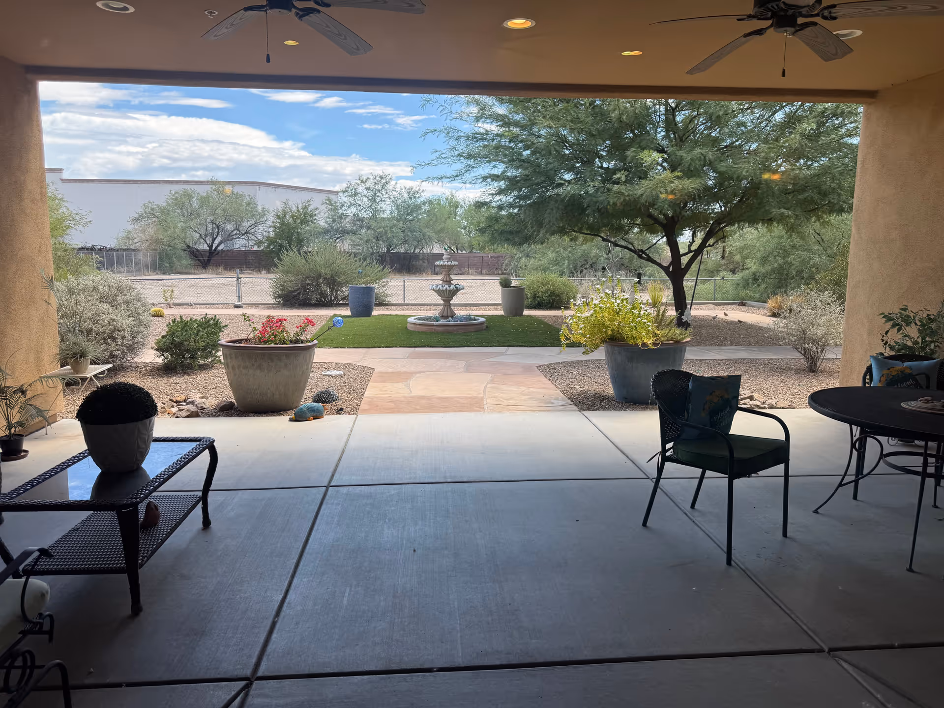 Covered patio view of a desert courtyard with a fountain and outdoor seating.