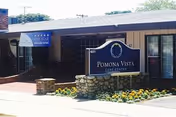 Exterior view of Pomona Vista Care Center with a stone sign and flower bed.