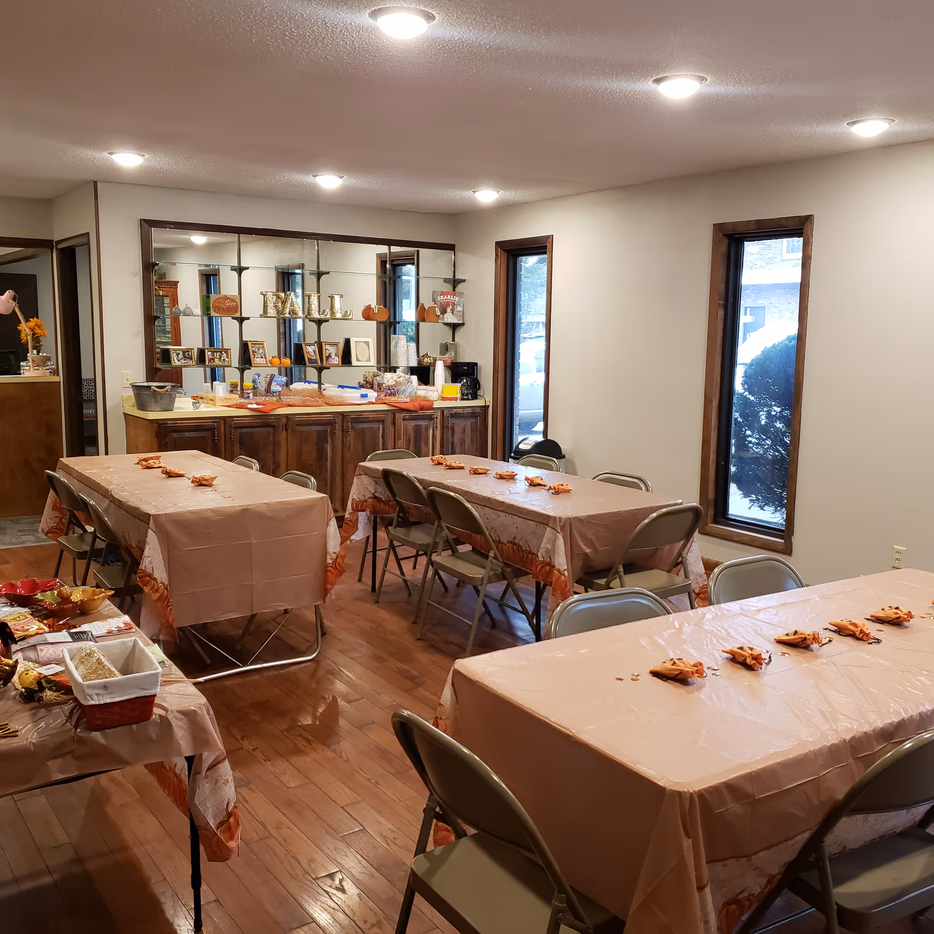 Dining room with long tables covered in pink tablecloths and folding chairs.