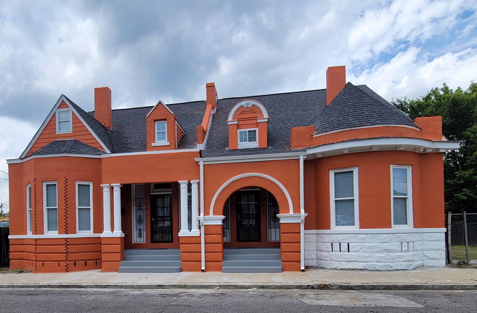 Exterior view of a red-orange brick senior living building with arched entrance and white trim.