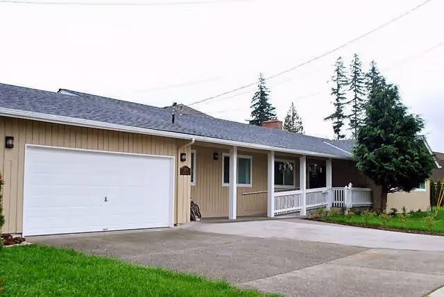 Single-story beige facility with a white garage door, front porch, and green lawn.