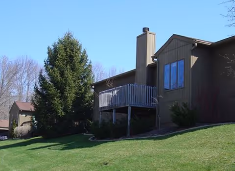 A Meadowood senior living building on a sloped lawn with a wooden deck.