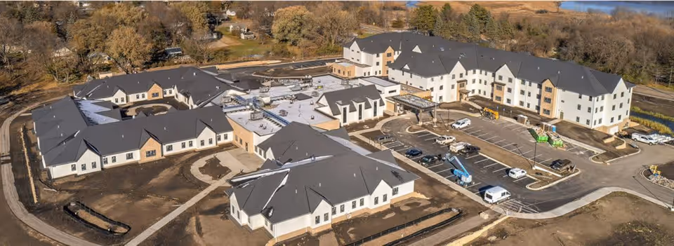 Aerial view of a large senior living facility complex named Haven Homes, showing multiple connected buildings with dark roofs, parking lots with several vehicles, and surrounding landscaping under construction.