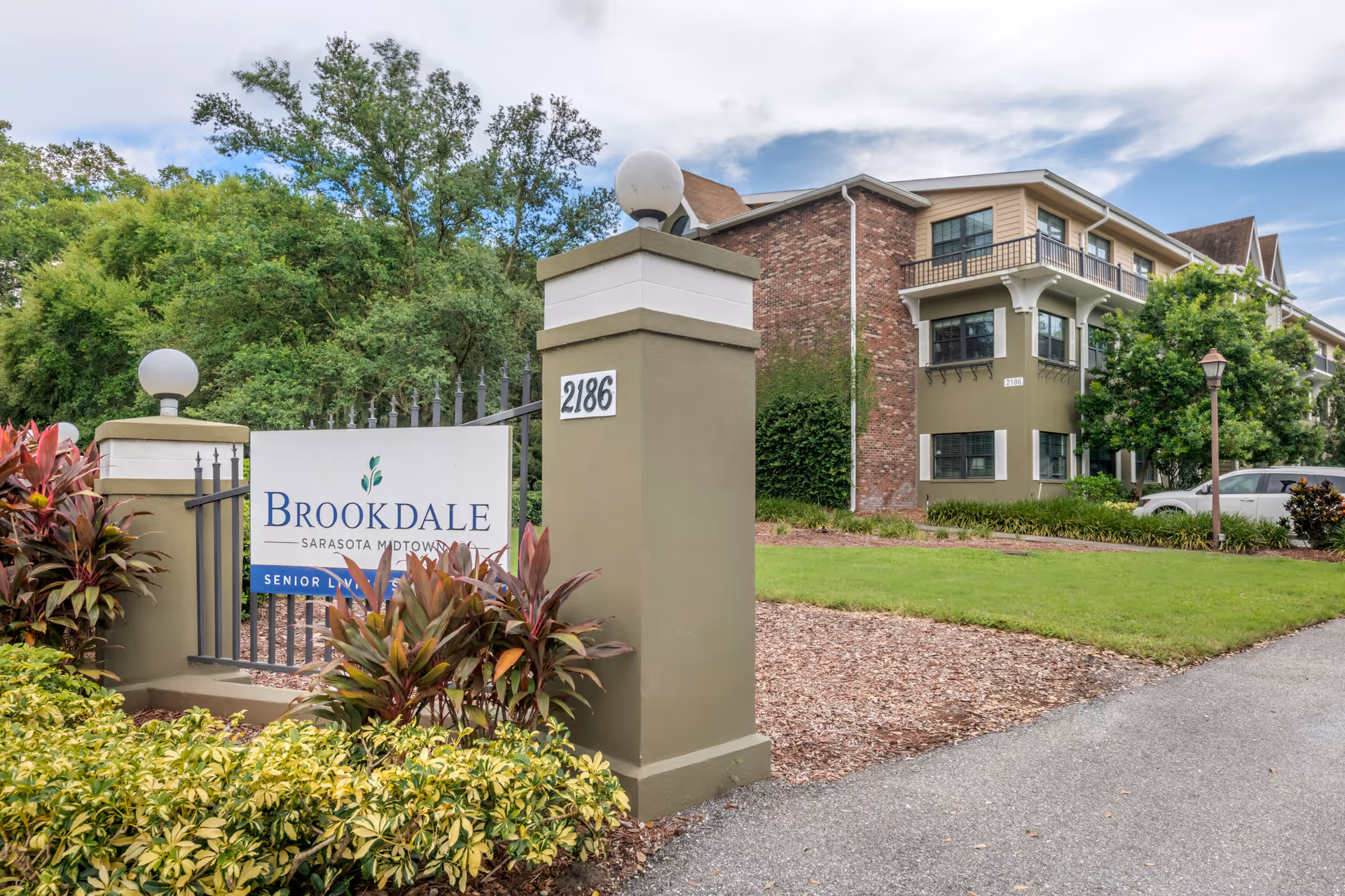 Exterior view of Brookdale Sarasota Midtown entrance with sign and landscaped front yard.
