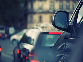 Row of cars in traffic with a side mirror in foreground.