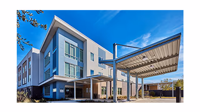 Modern senior living facility exterior with blue facade and covered entrance.