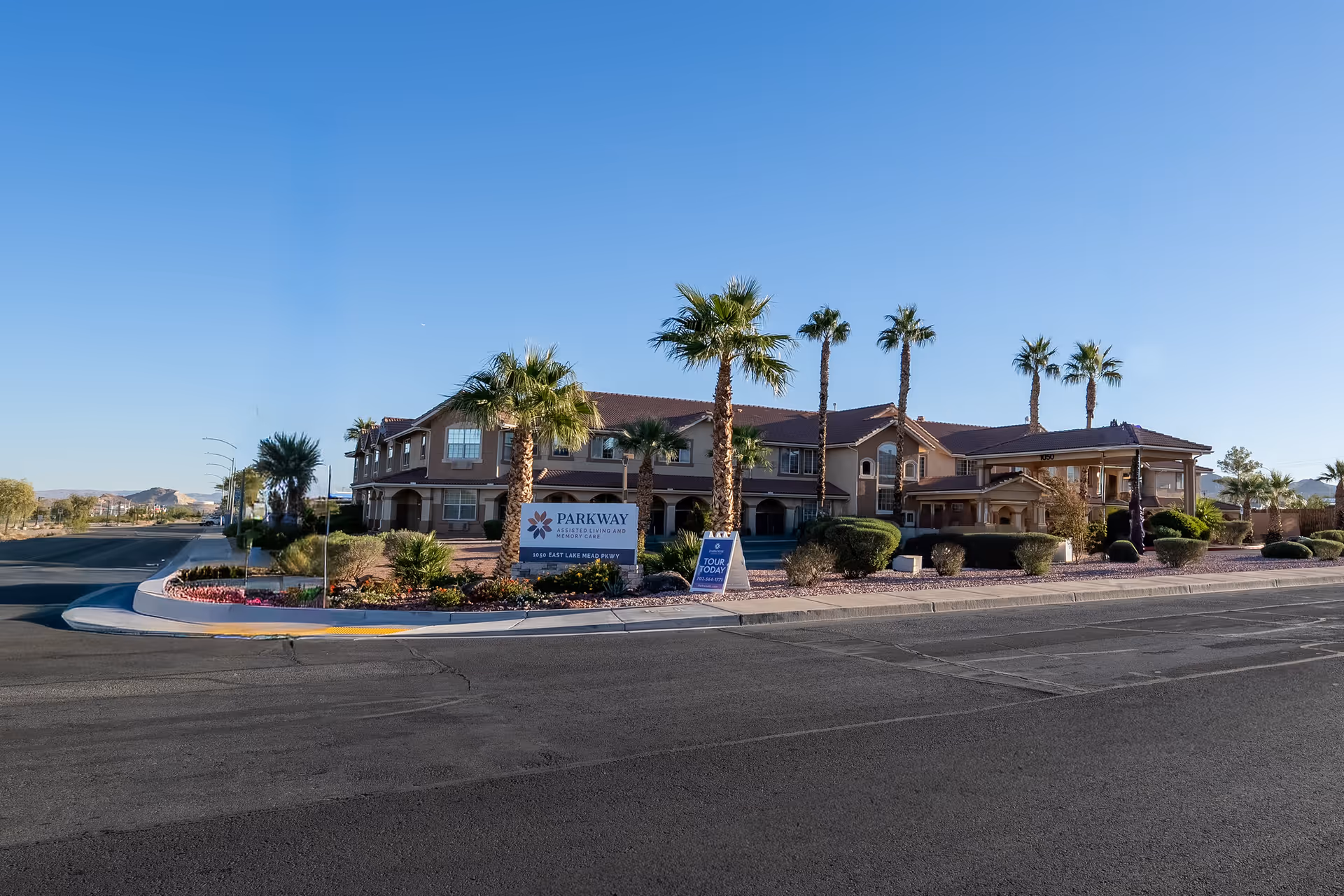 Exterior view of Parkway Assisted Living building with palm trees, signage, and landscaping.