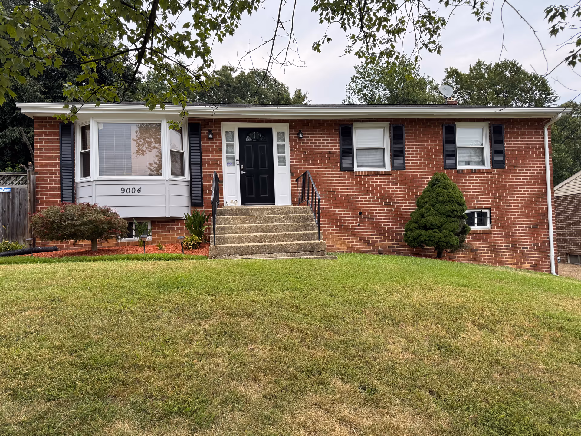 Front view of a single-story brick house with stairs to a black front door.