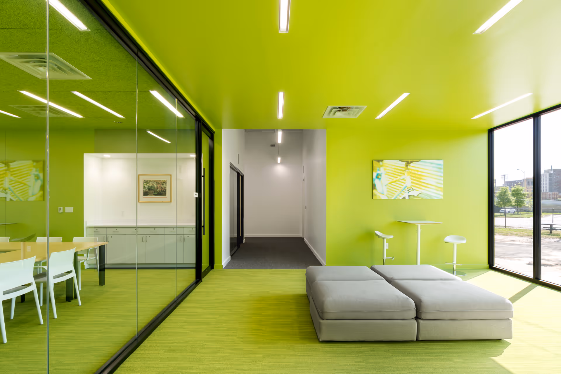 Bright lime-green interior lounge with glass partitions, modern seating, and large windows.