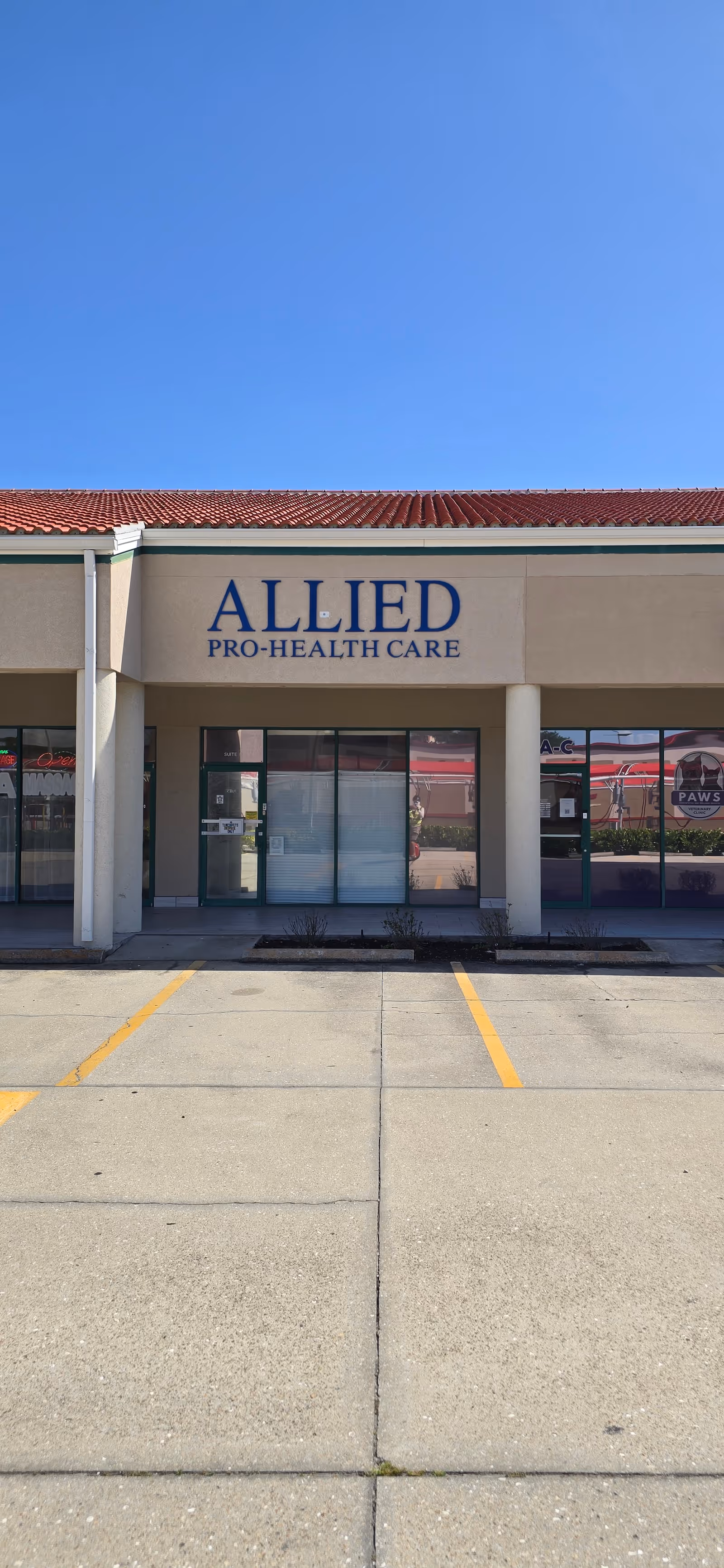 Exterior storefront of Allied Pro-Health Care with glass doors and blue sky