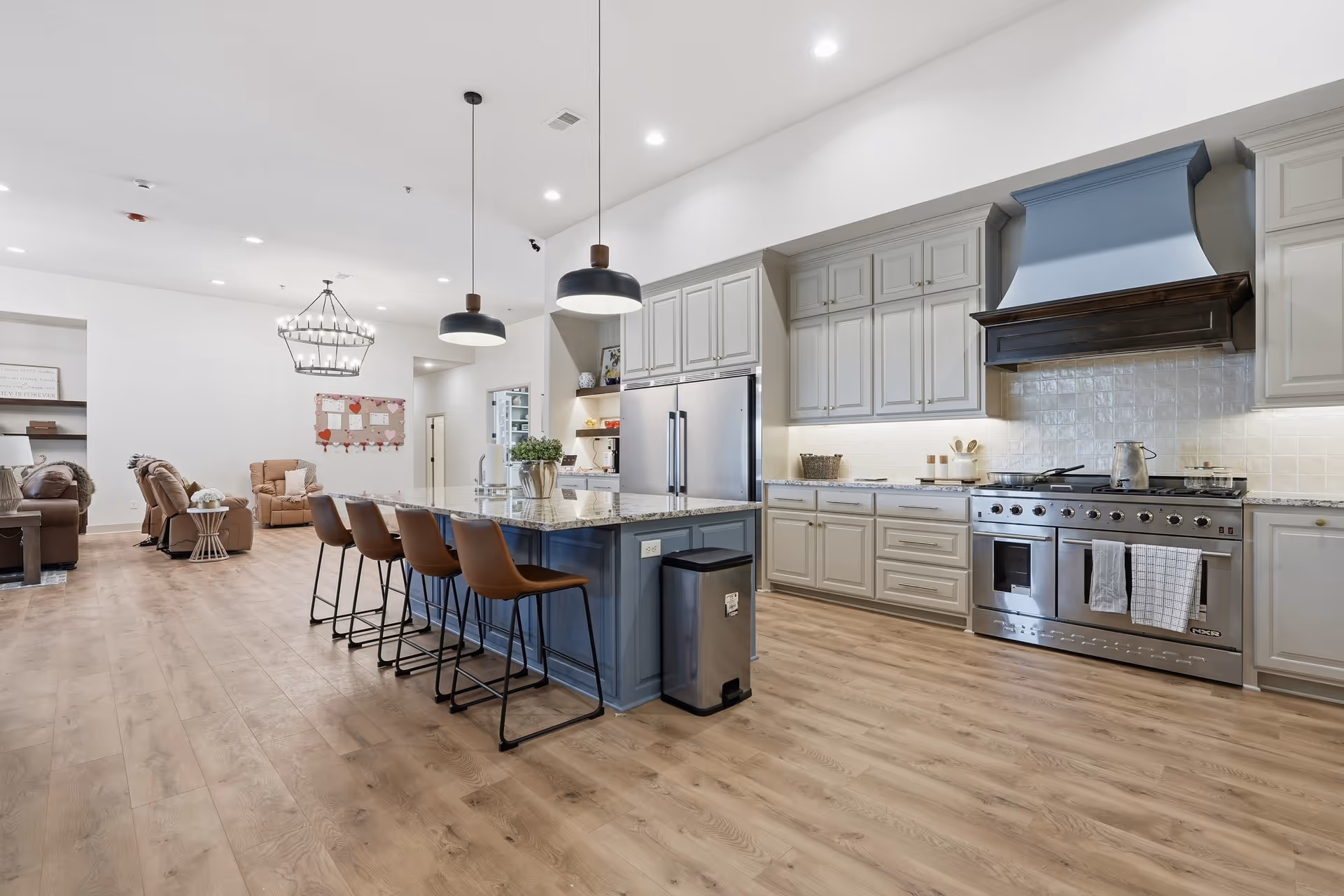 Bright open kitchen with a large island, seating, stainless steel appliances, and light wood flooring.