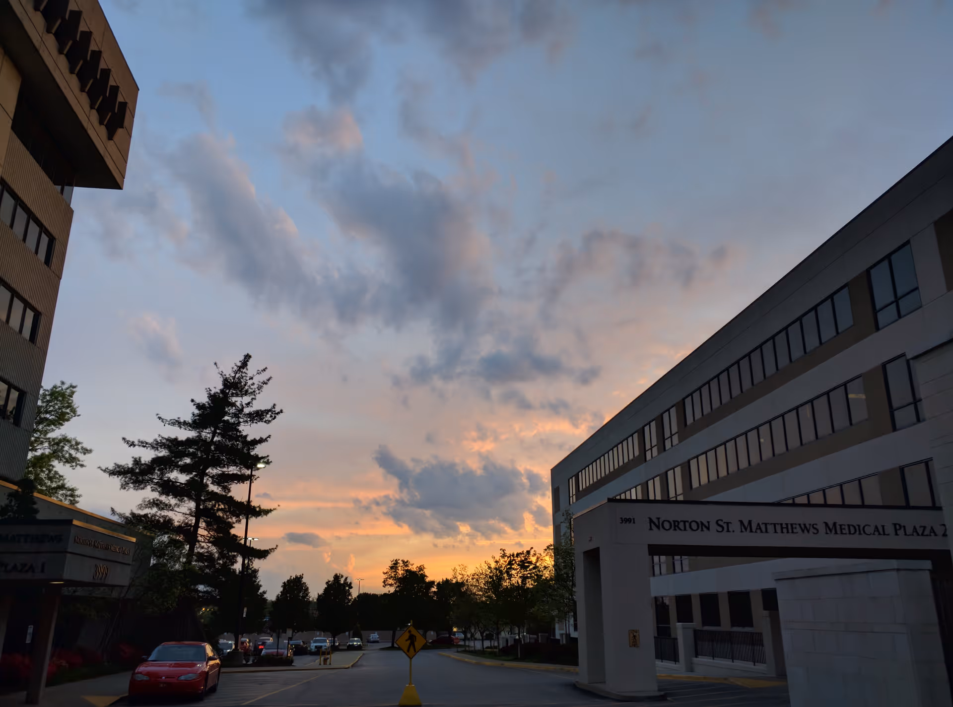 Sunset sky above Norton St. Matthews Medical Plaza 1 exterior with cars in the lot.