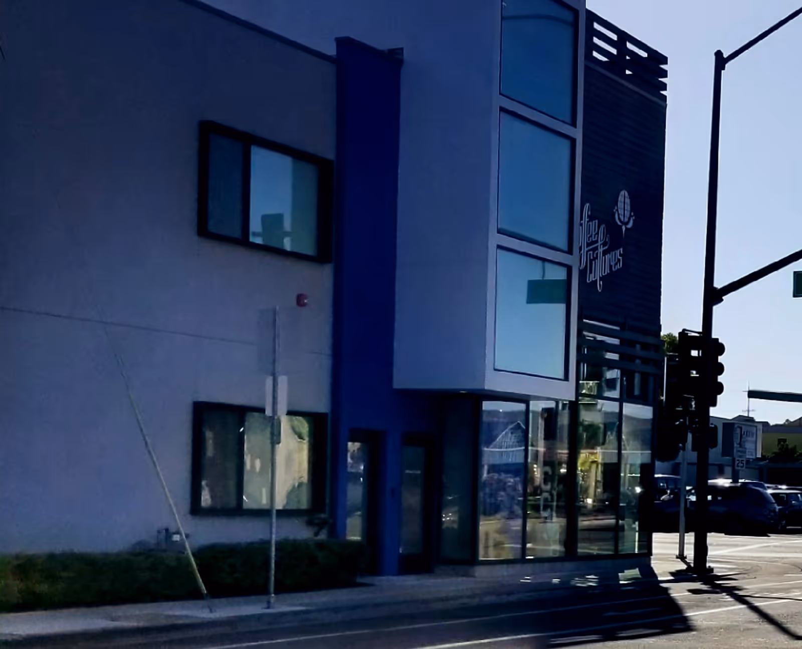 Street-facing exterior of a modern building with glass storefront and blue accents.