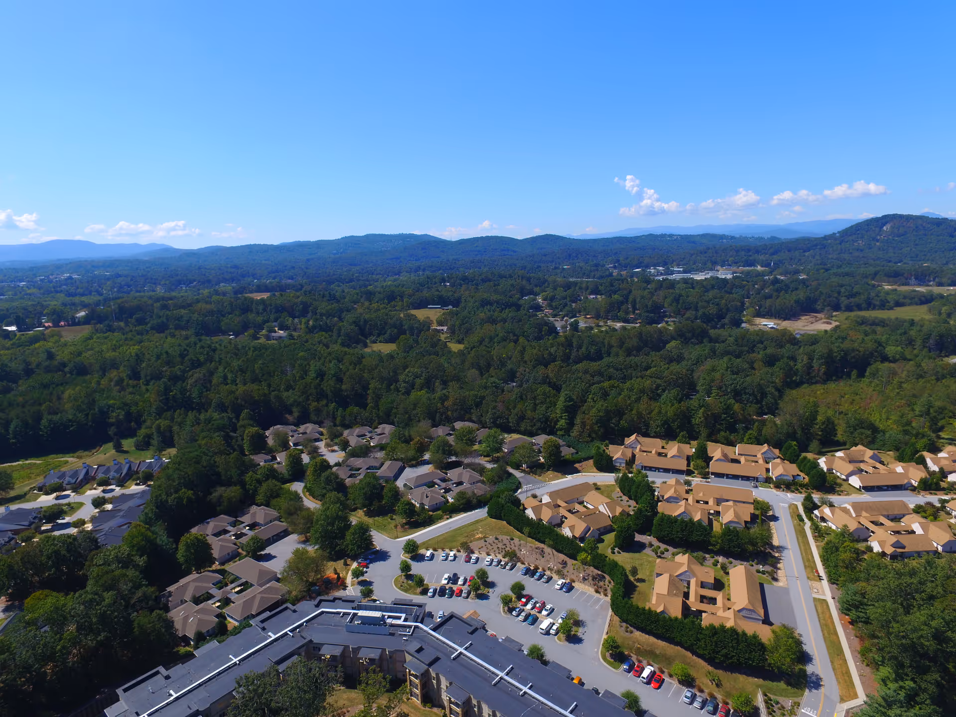 Aerial view of Carolina Village campus with clustered residential buildings, roads, and green hills.