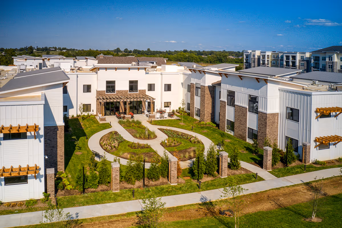 A Preston Greens Senior Living campus with white buildings and a central landscaped courtyard.