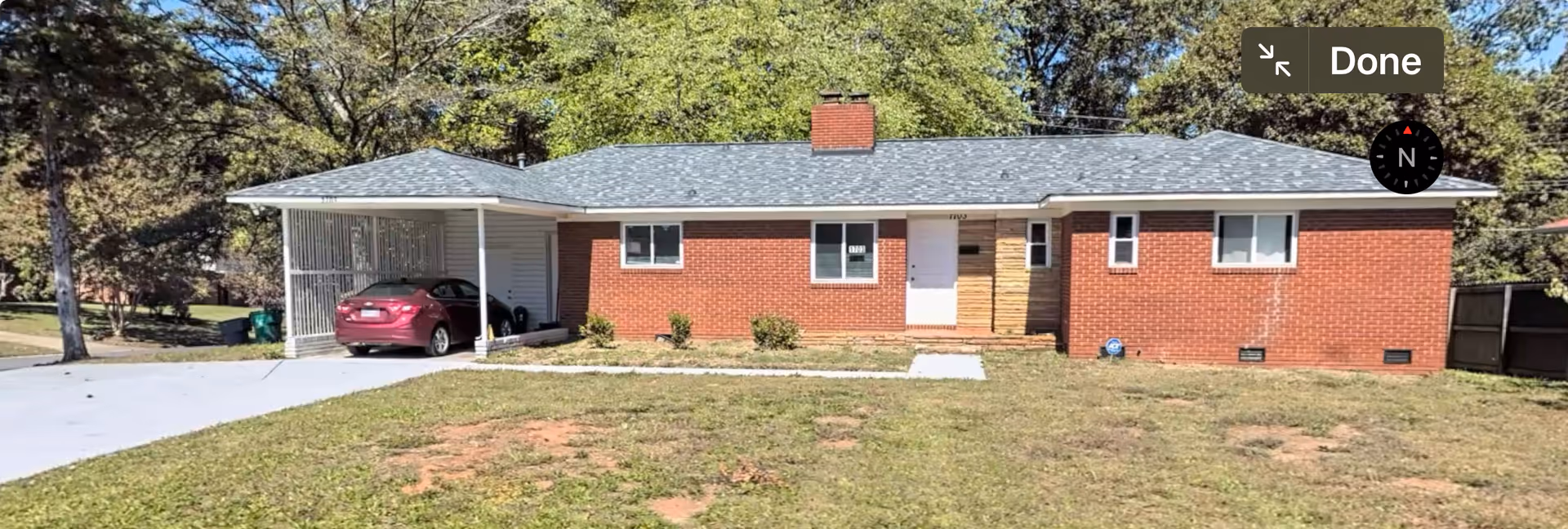 Exterior of a single-story brick building with a car under a covered carport.