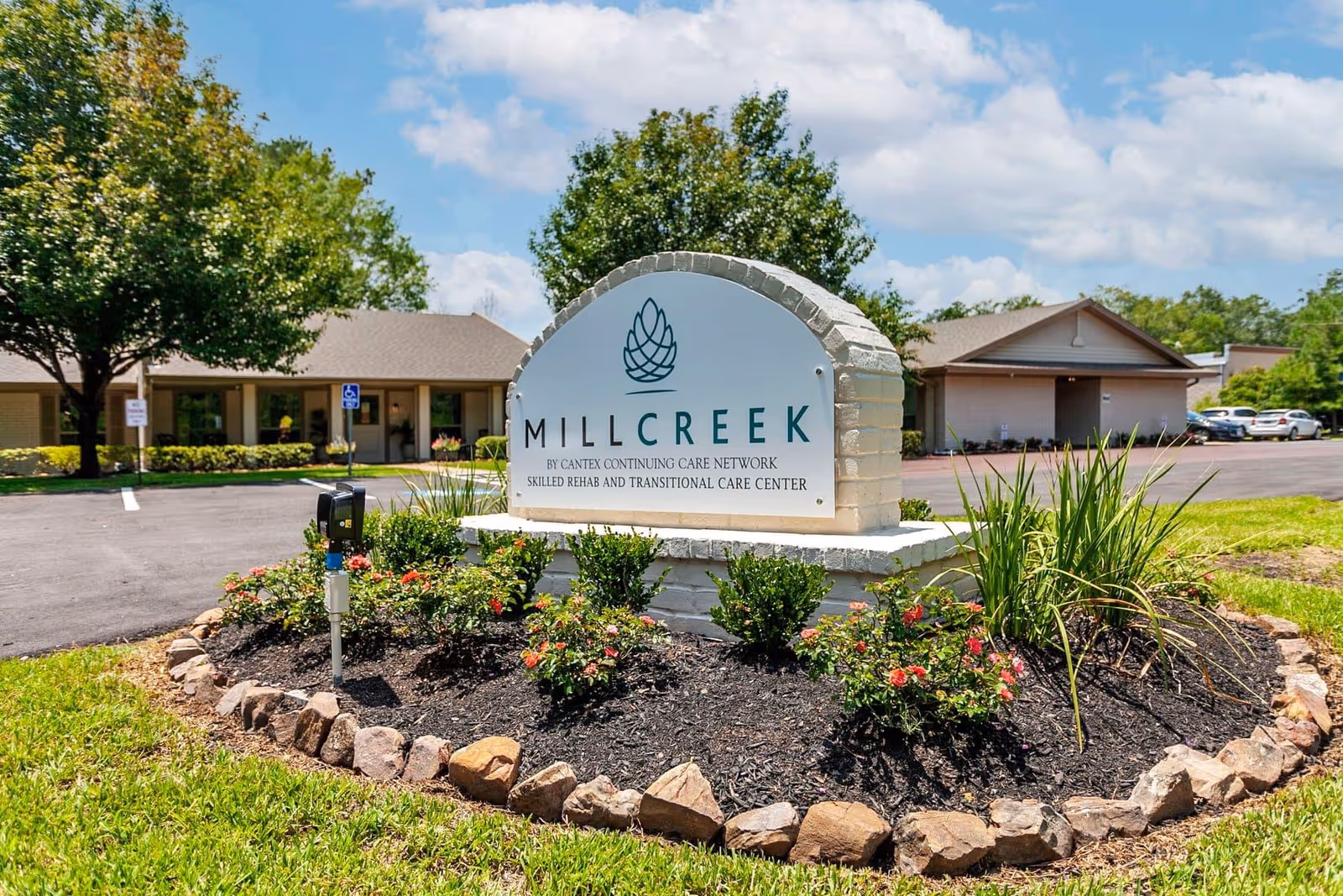 Front exterior view of Millcreek convalescent center sign with landscaped bed.