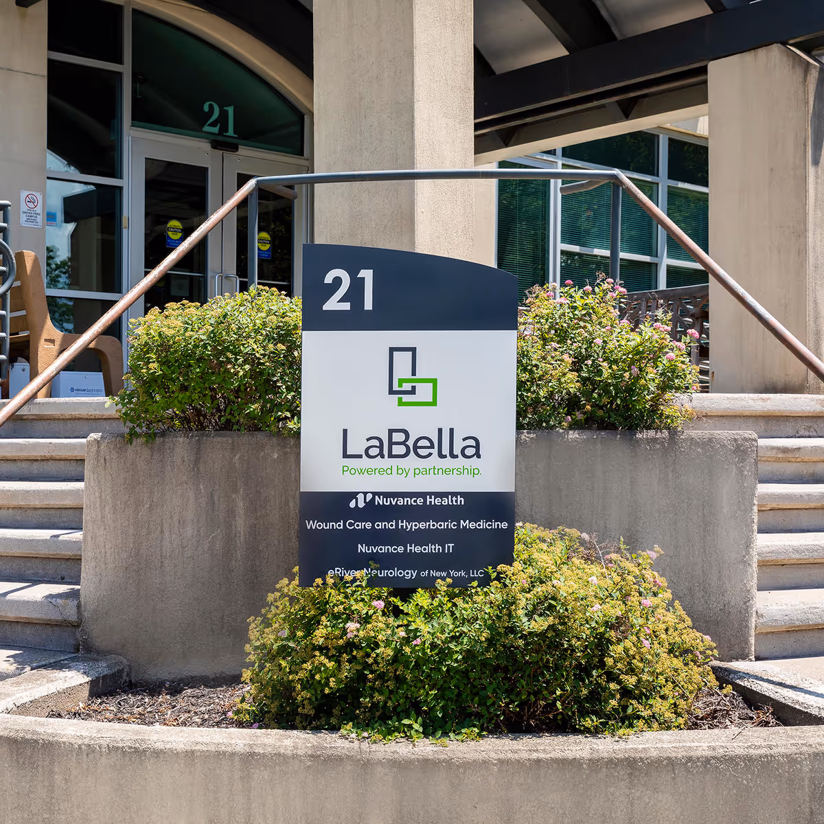 Exterior entrance with LaBella sign, building number 21, and landscaped shrubbery.