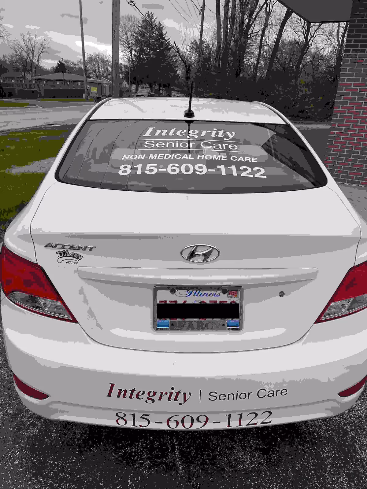 Rear of a white car with Integrity Senior Care branding and phone number.
