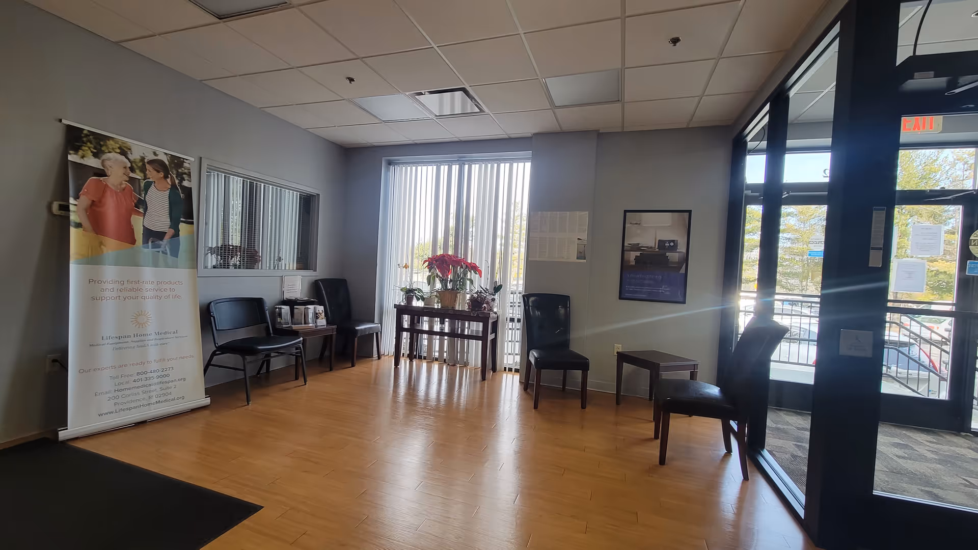 A waiting area with chairs, a banner, plants, and glass doors in a medical lobby.