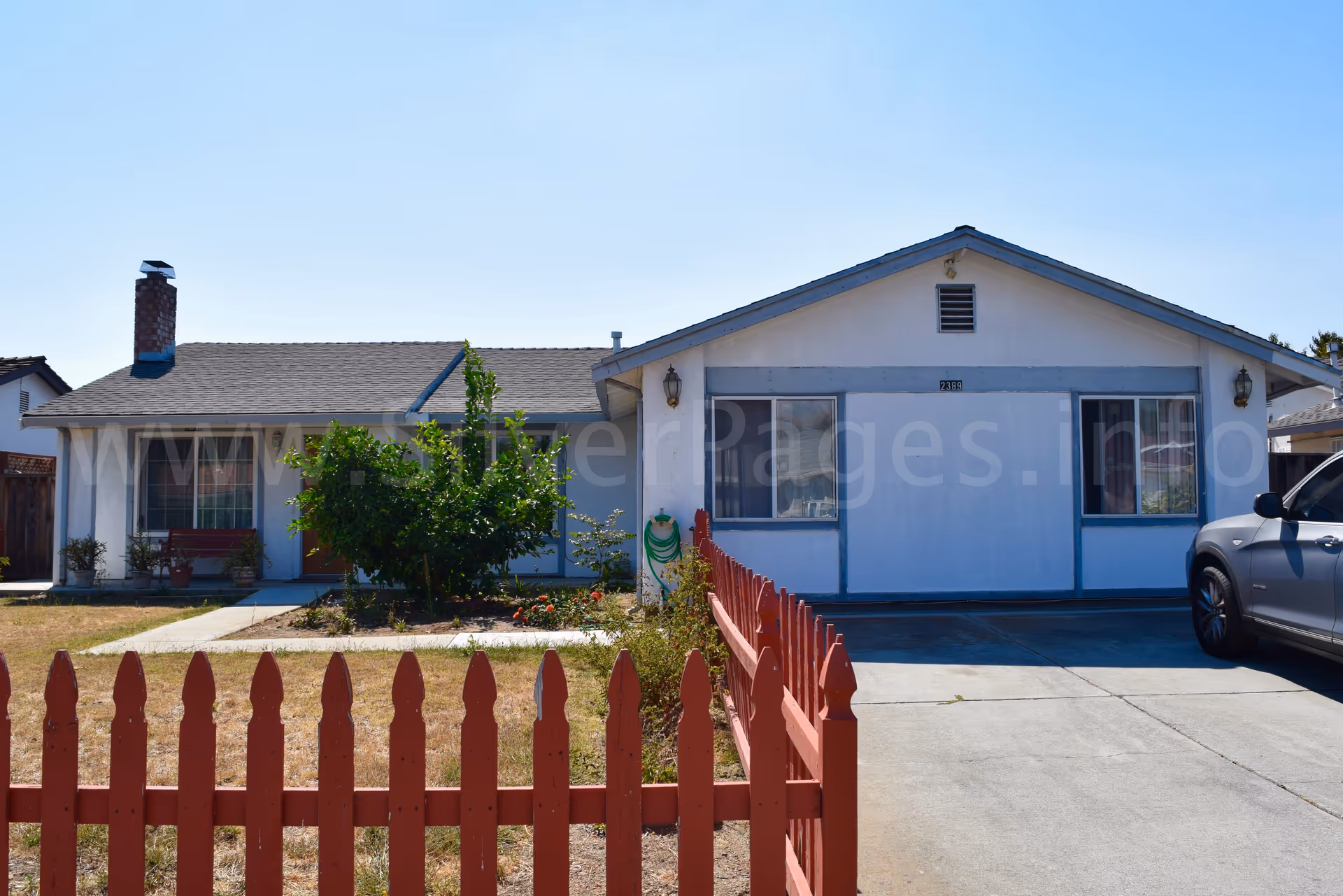 Front view of Mina's Elderly Care Home 3, a single-story house with a red picket fence.