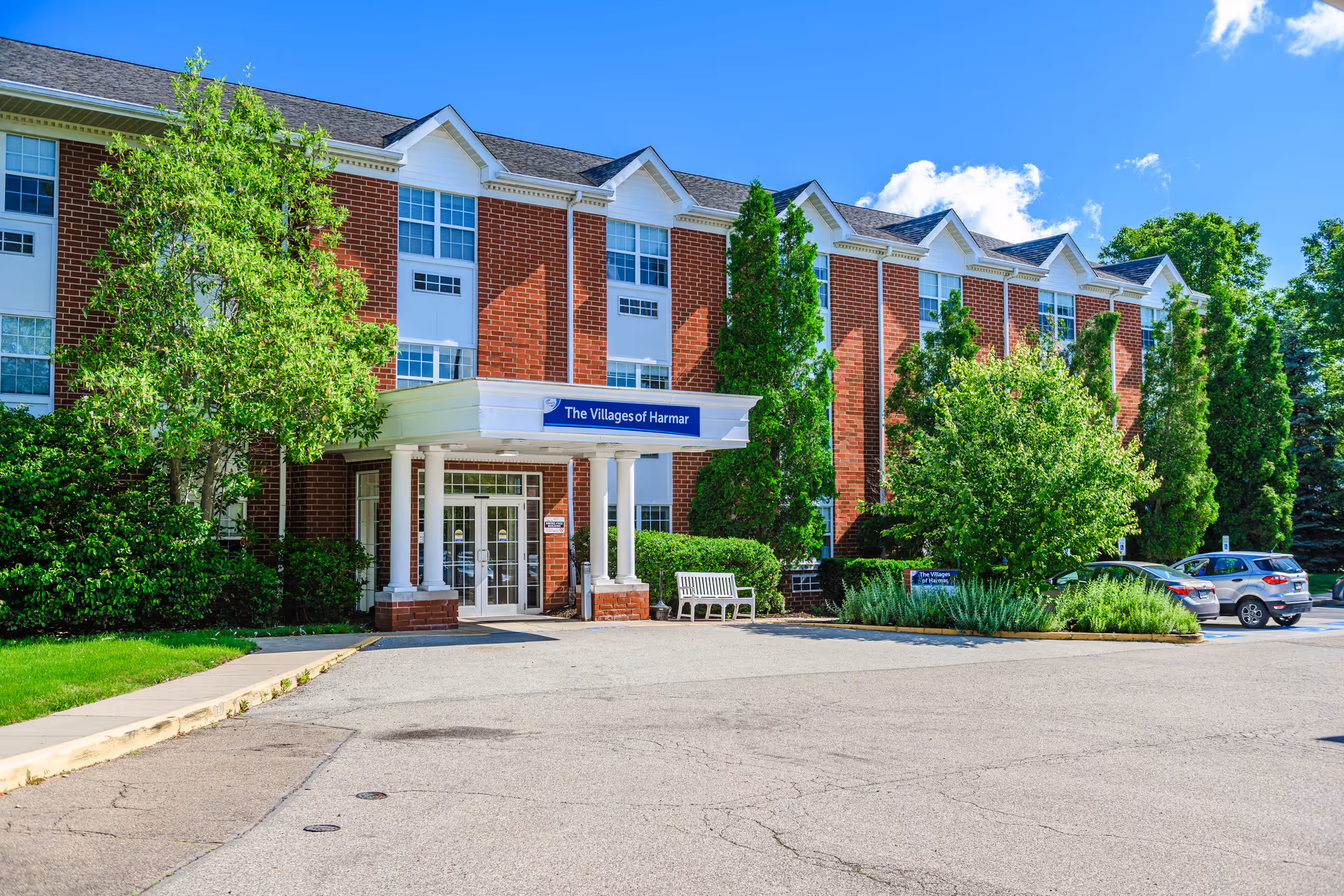 The Villages of Harmar brick senior living building with entrance and parking.
