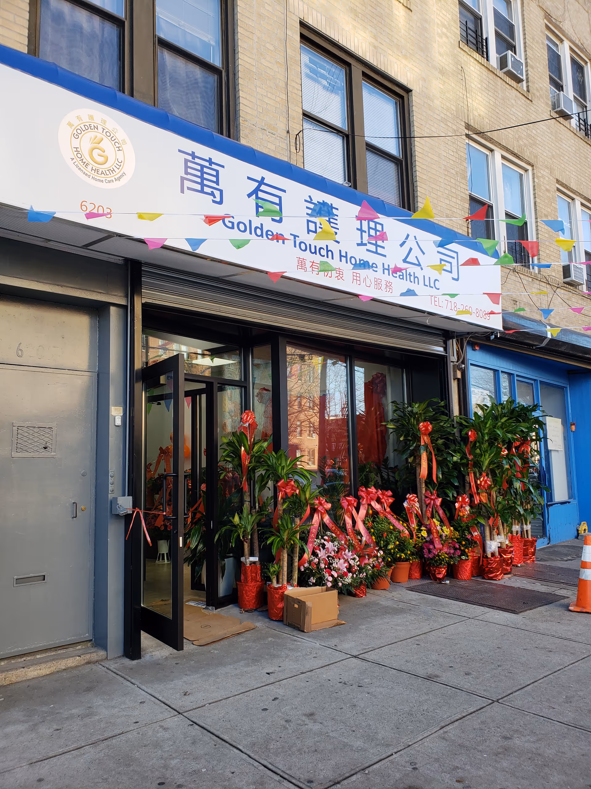Exterior of Golden Touch Home Health LLC storefront with colorful plants and banners.