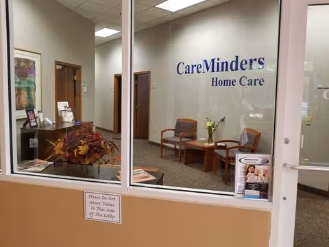 Interior reception area with CareMinders Home Care signage, seating, and plants.