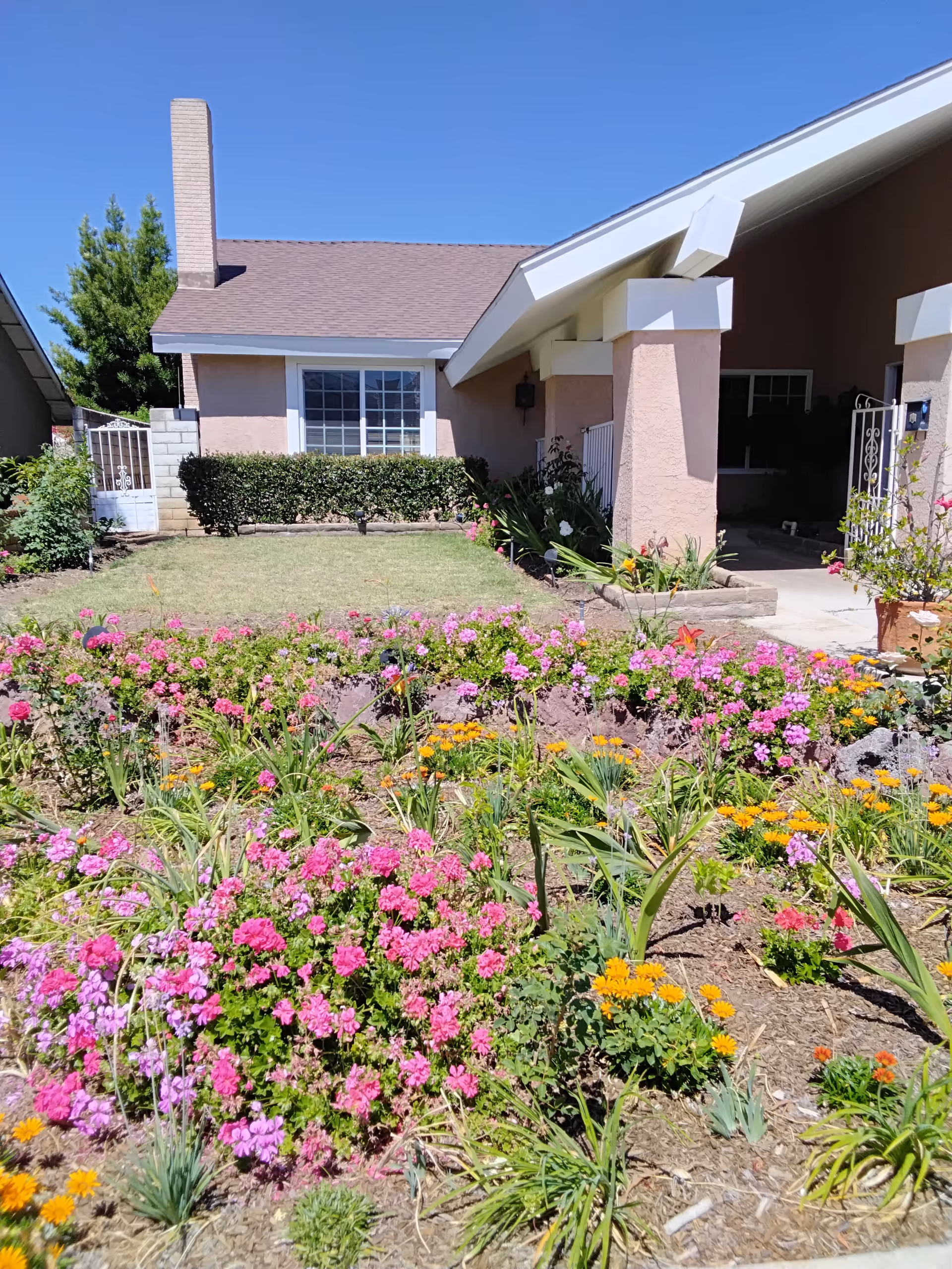 Front exterior of Golden Heritage Assisted Living with a vibrant flower garden and entryway.