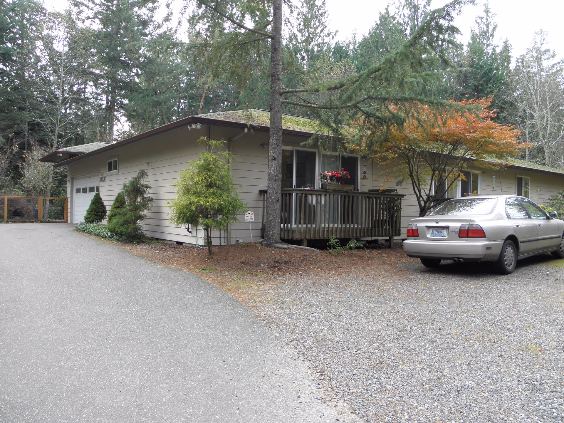 Single-story Harbor Heritage Adult Family Home exterior with a porch, trees, and a parked car.