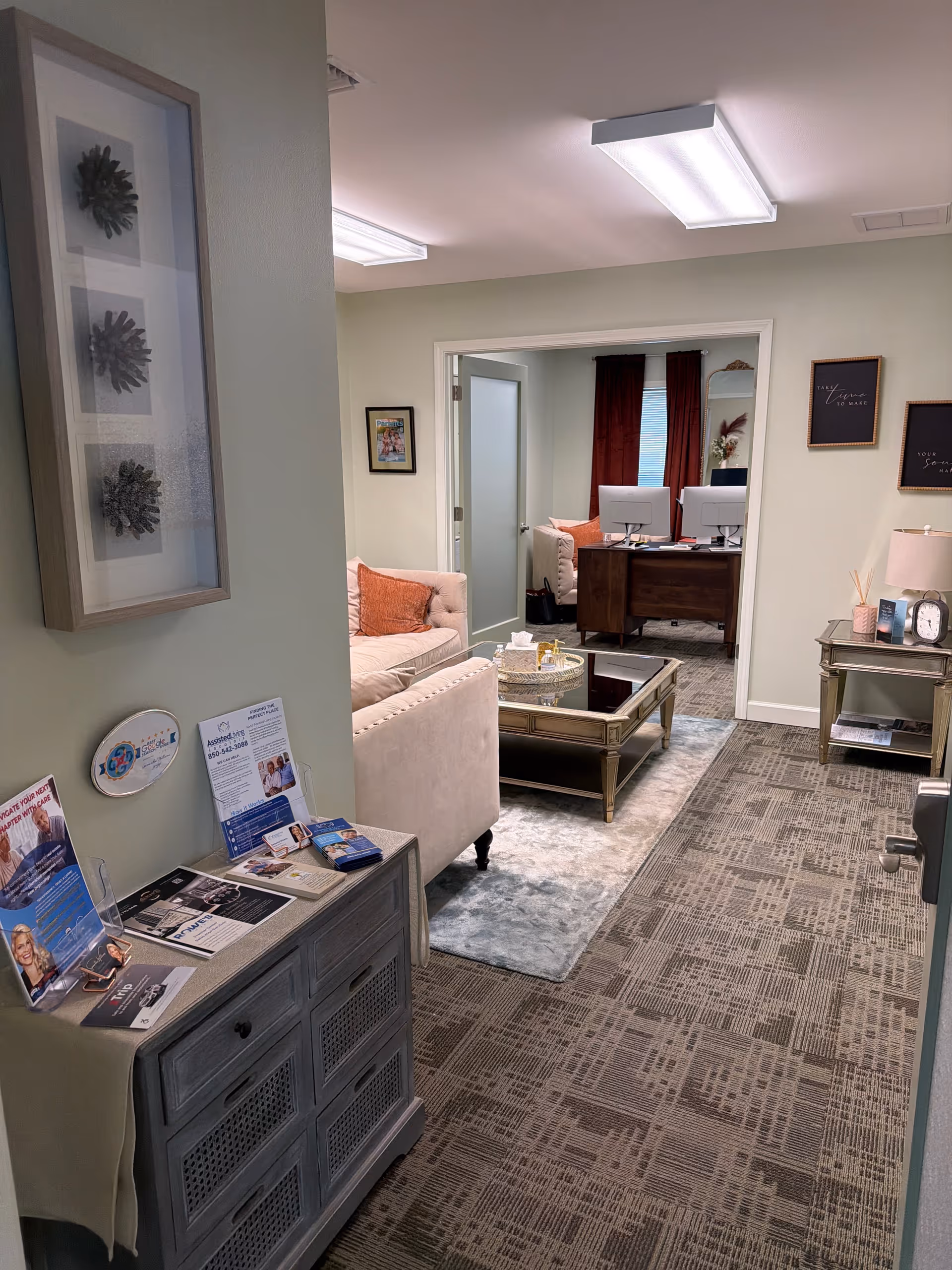 Interior reception lounge with beige sofas, glass coffee table, and brochures.