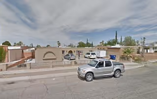 A single-story beige senior living facility facade with arches and a pickup truck in front.