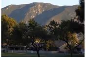 Exterior view of Leisure Village Camarillo with a front building, trees, and mountains.