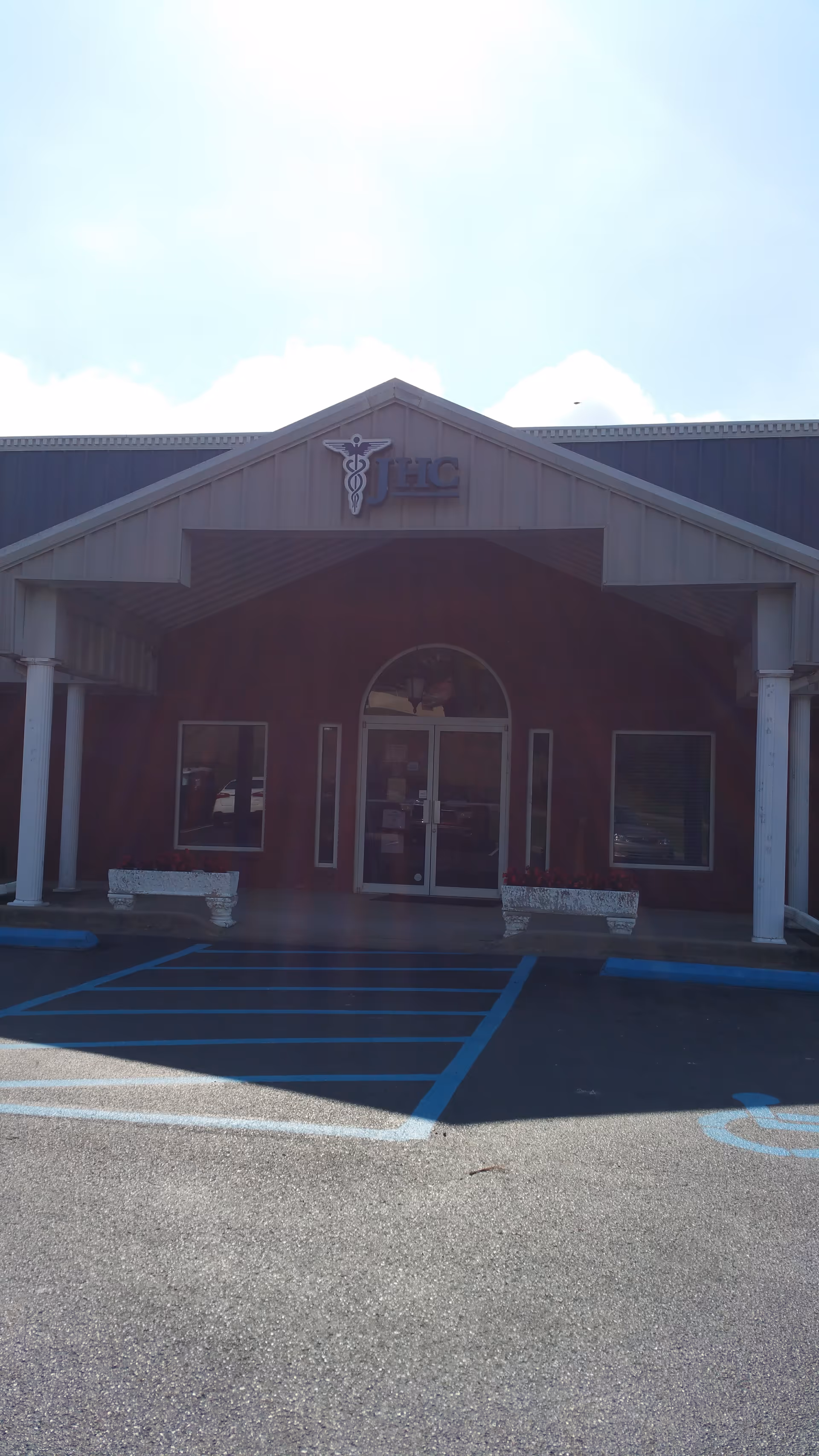 Front entrance of Jernigan Healthcare facility, red brick building with arched doorway and handicap parking.