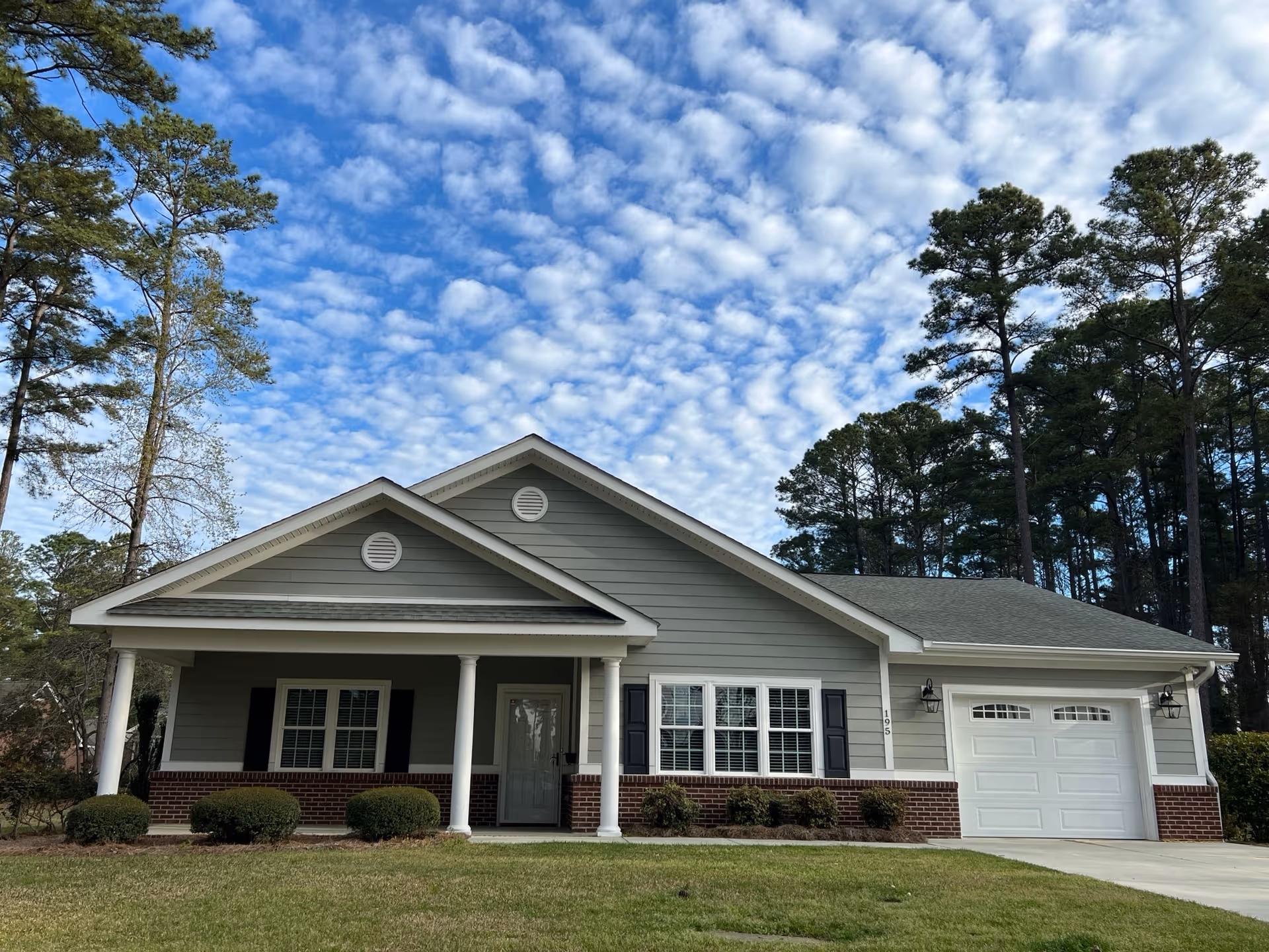 Front exterior of Wesley Pines retirement community building with porch, driveway, and surrounding trees.