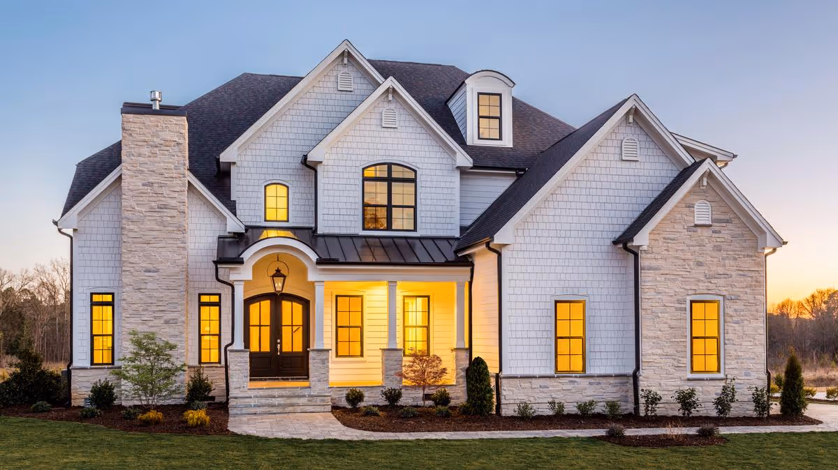Front view of a large white house-style facility with stone accents and lit windows.