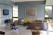Bright communal living area with seating, a map, TV, and yellow flowers.