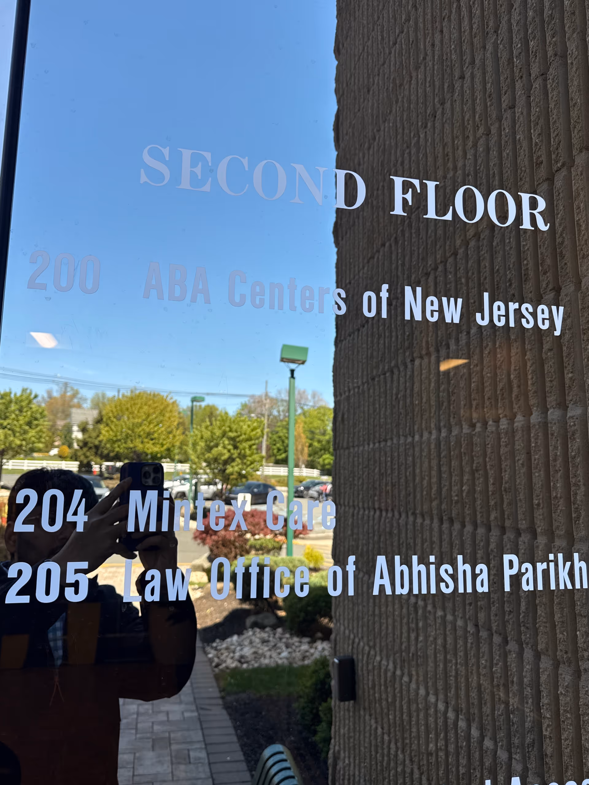 Exterior glass door with Second Floor and Mintex Care signage; photographer reflection visible.