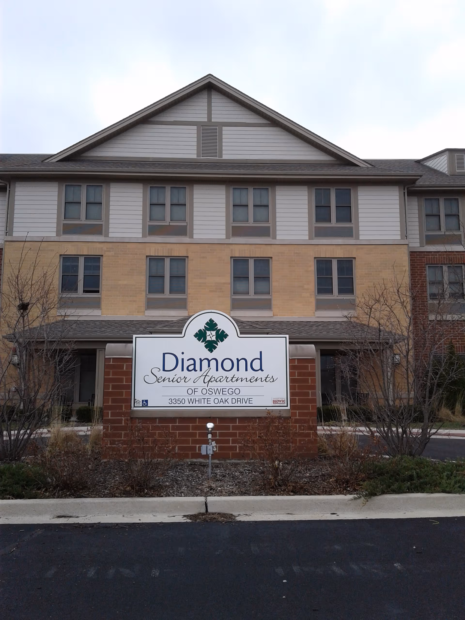 Front view of Diamond Senior Apartments building in Oswego with a large sign.