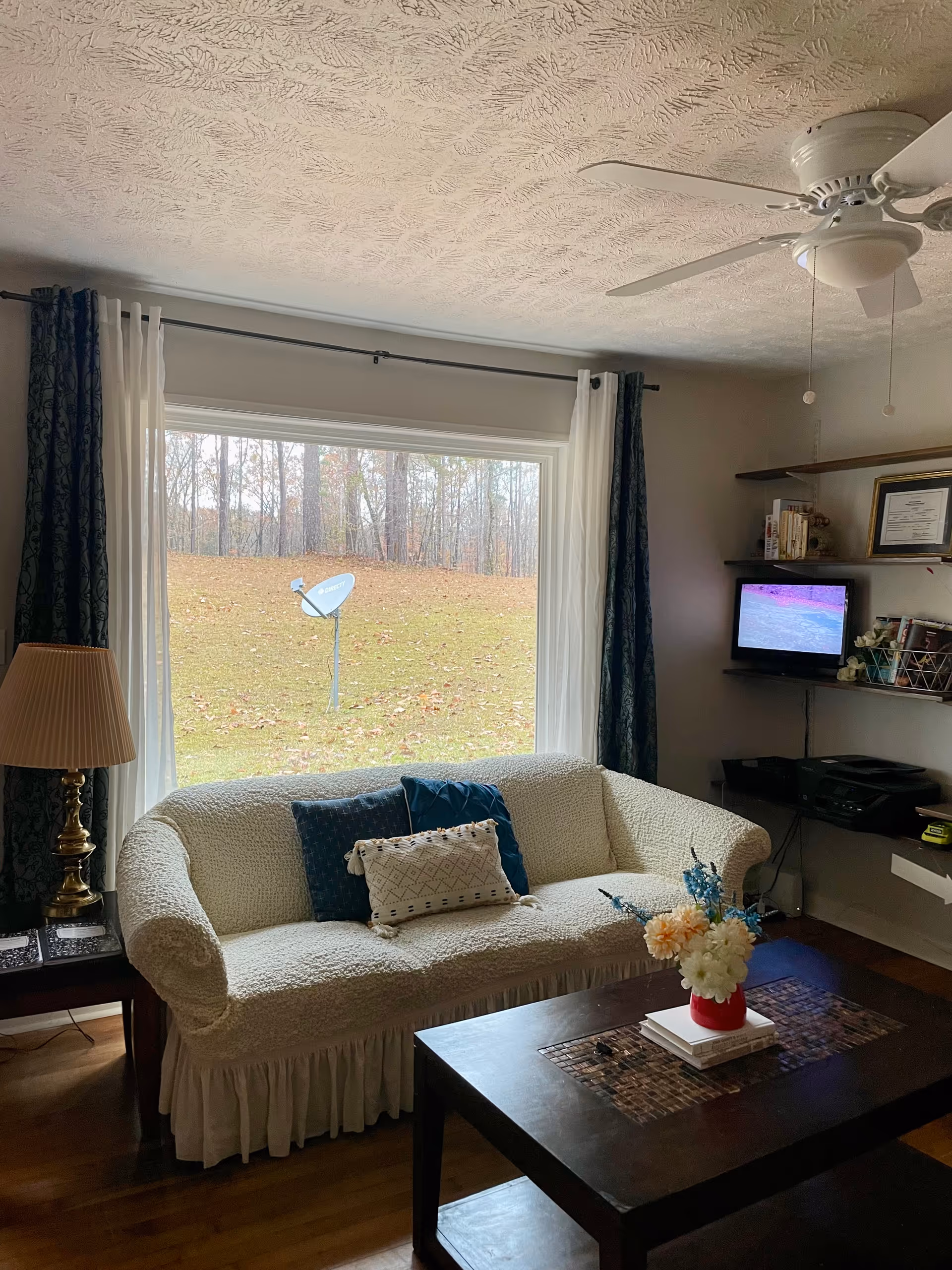 Cozy living room with a white sofa and a view of the yard through the window