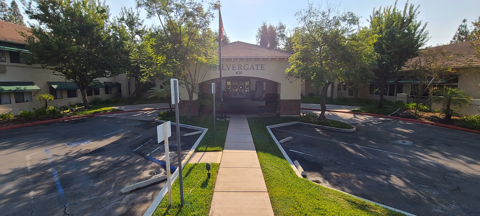 Front view of Silvergate Fallbrook Retirement entrance with trees and parking.