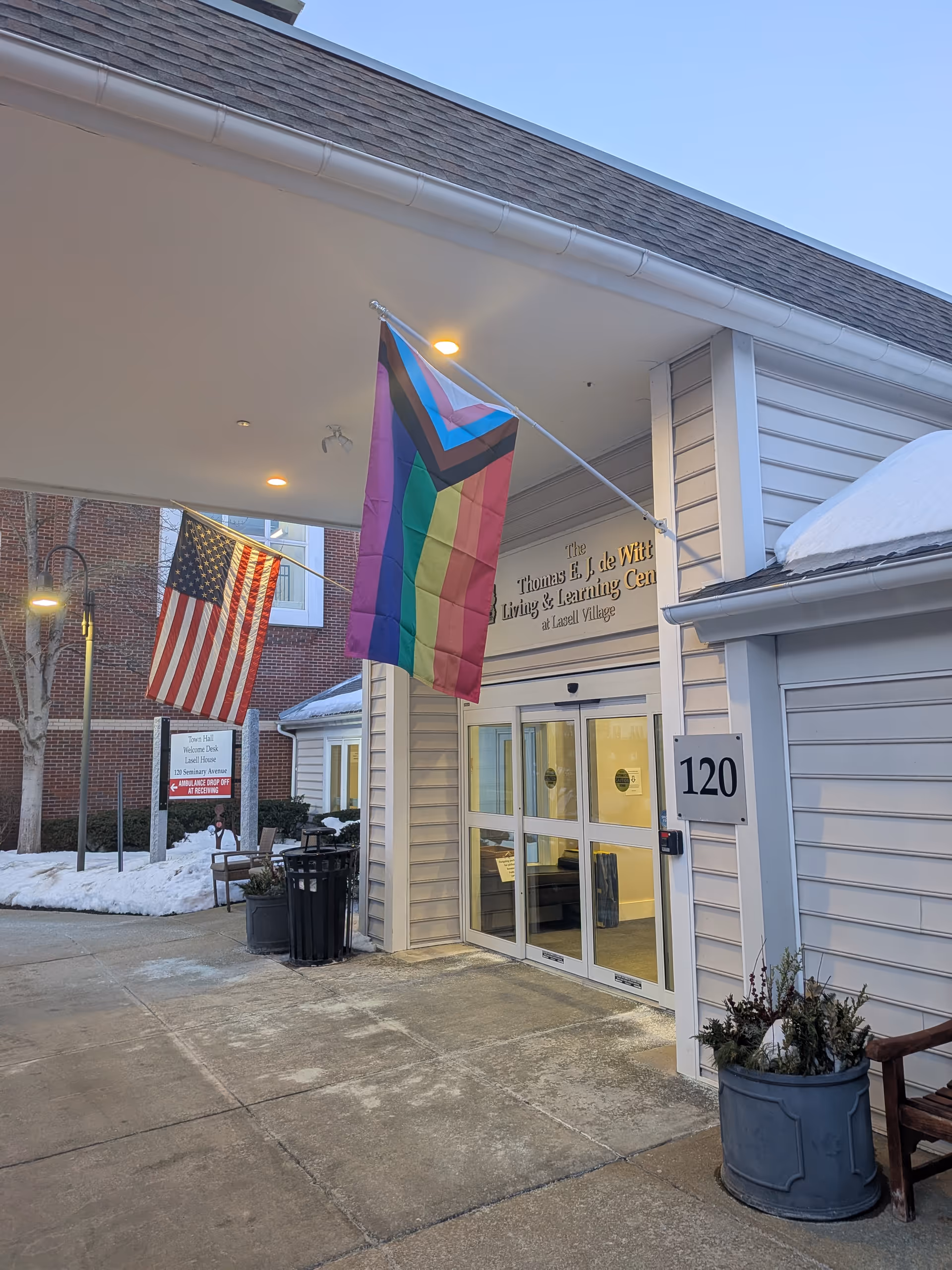 Exterior view of Lasell Village entrance with American and LGBTQ pride flags.
