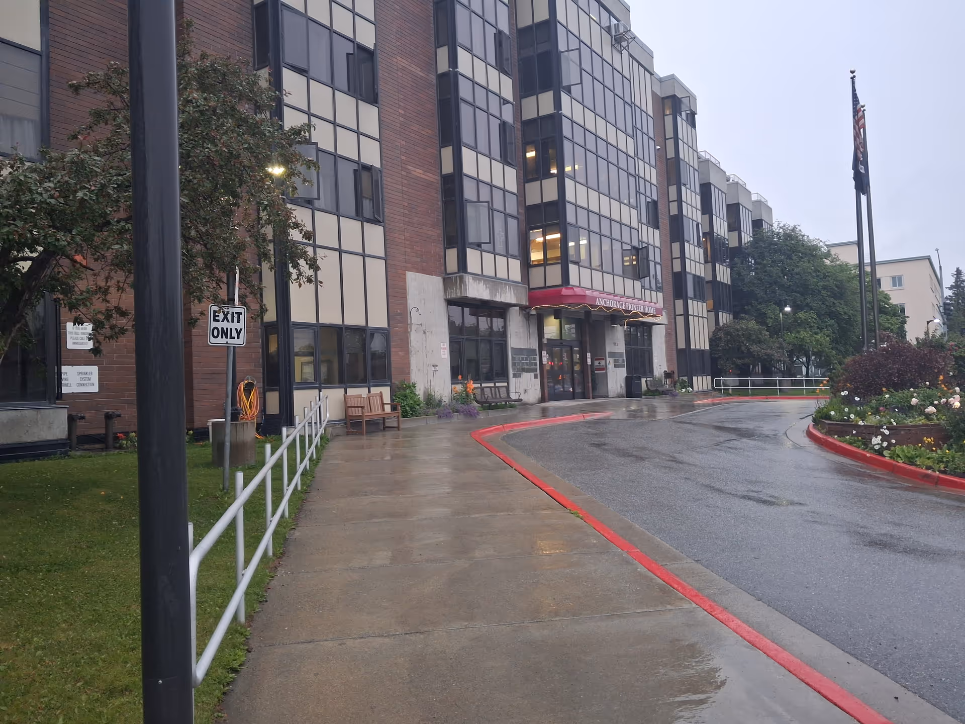 Front view of Pioneers' Home I entrance with red awning and wet pavement.