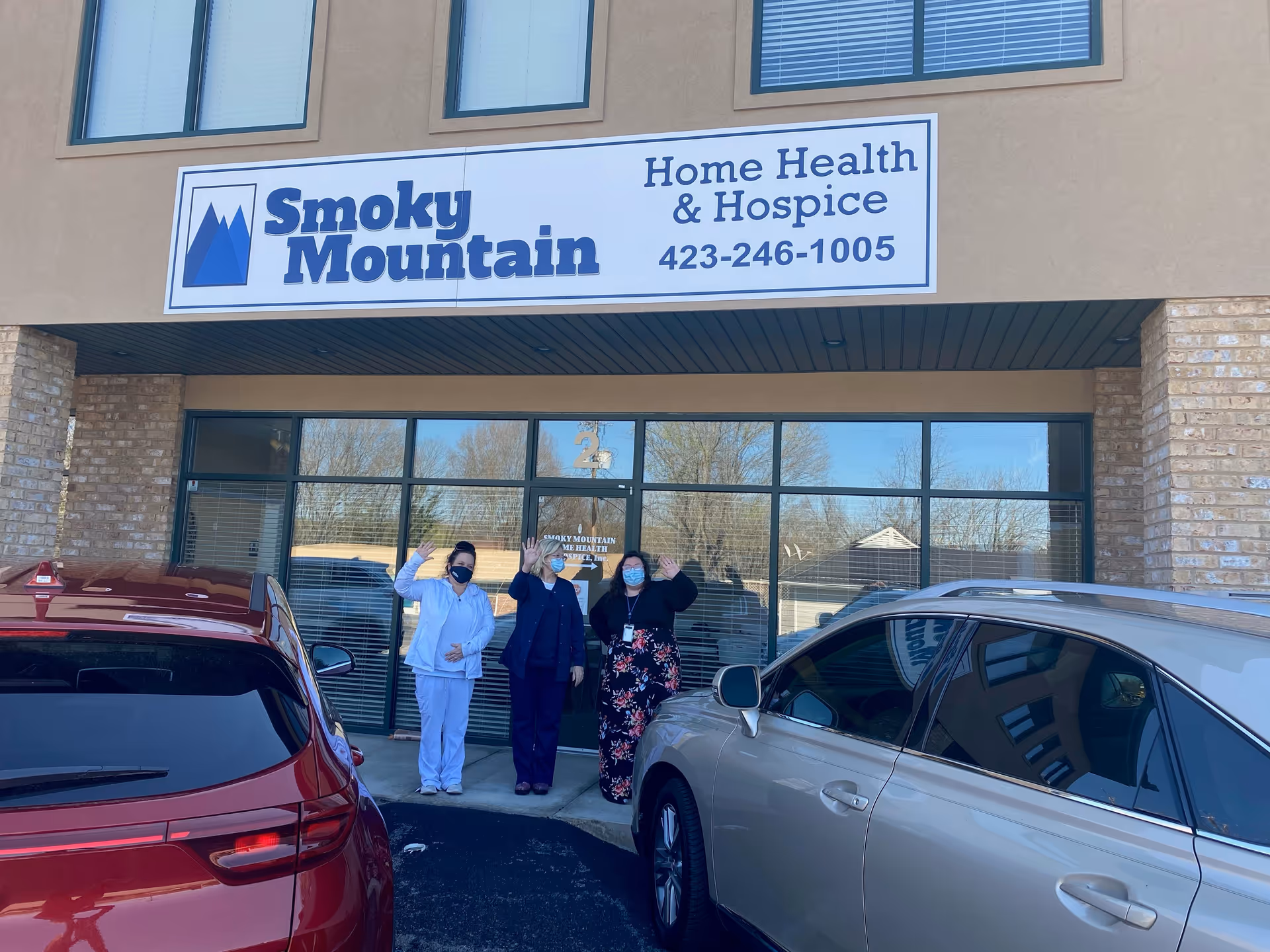 Three people wearing masks stand in front of Smoky Mountain Home Health & Hospice entrance.