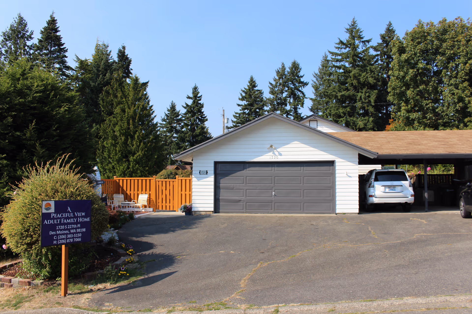 Front view of a single-story adult family home with a two-car garage and vehicles.
