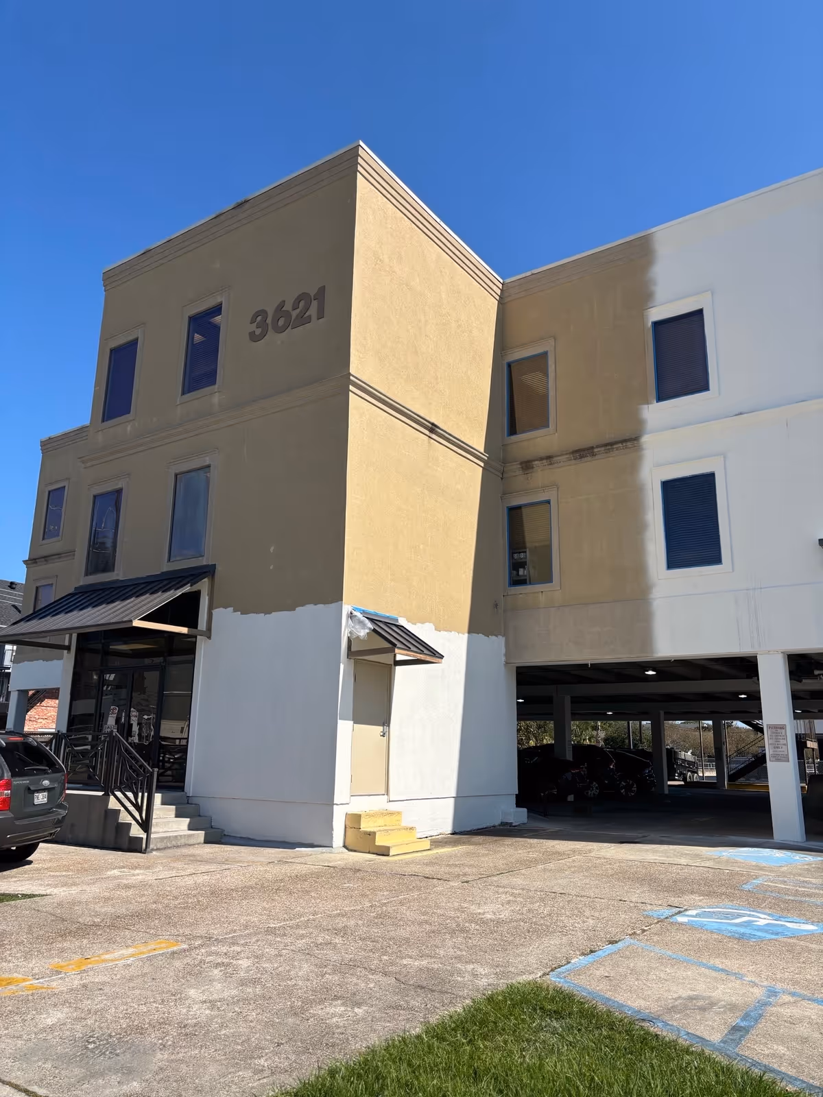 Exterior view of a beige multi-story building with 3621 on the wall and a parking area.